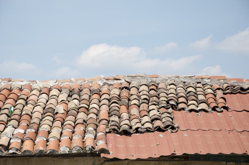 Weathered roof surface with tile and shingles roofing material architectural detail on blue sky