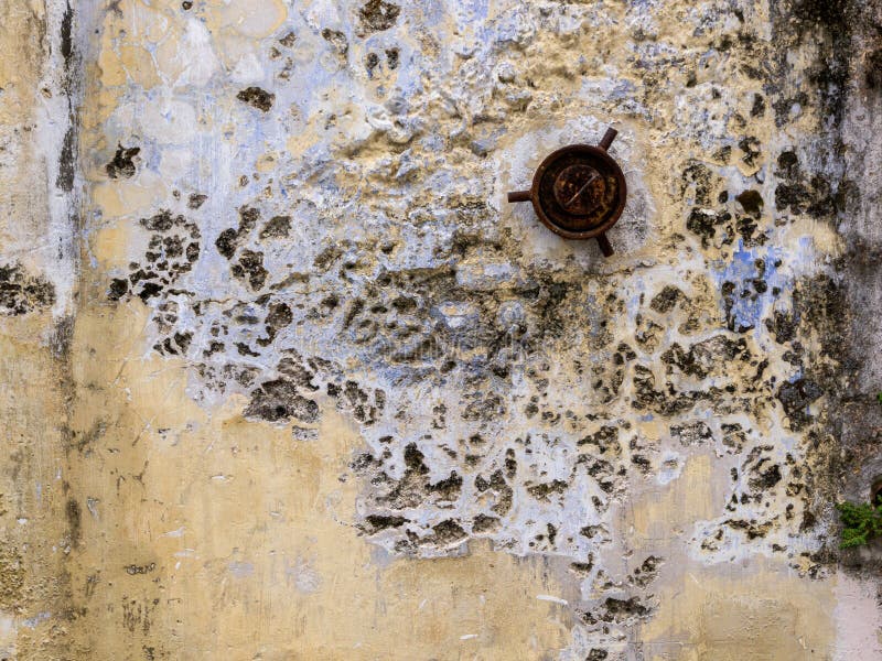 Weathered textured yellow walls with cracks and a drain outlet. royalty free stock photo