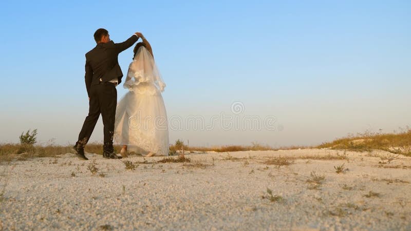 Weddenschap op huwelijksreis Romantische man en vrouw dansen in het zand tegen de hemel