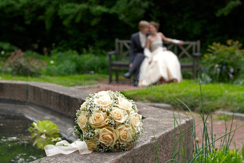 Wedding bouquet with bride and groom in background