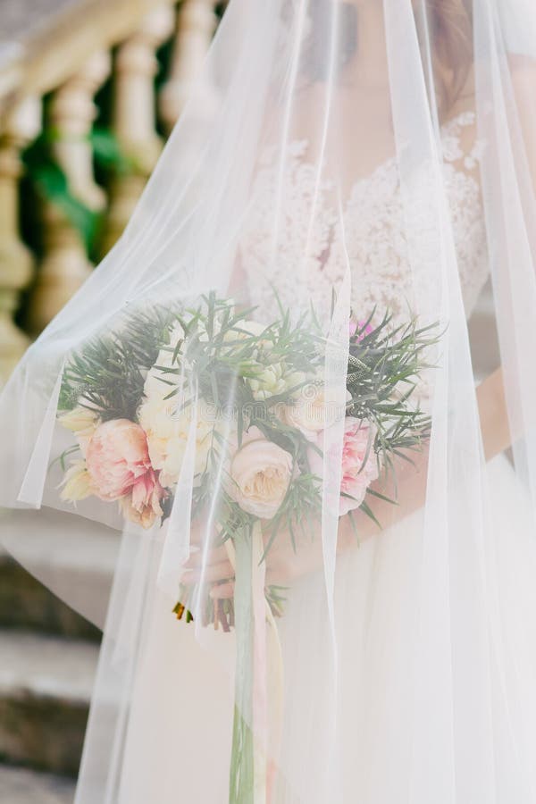 Wedding bouquet of peonies in the hands of the bride. Wedding in. Closeup, fashion.