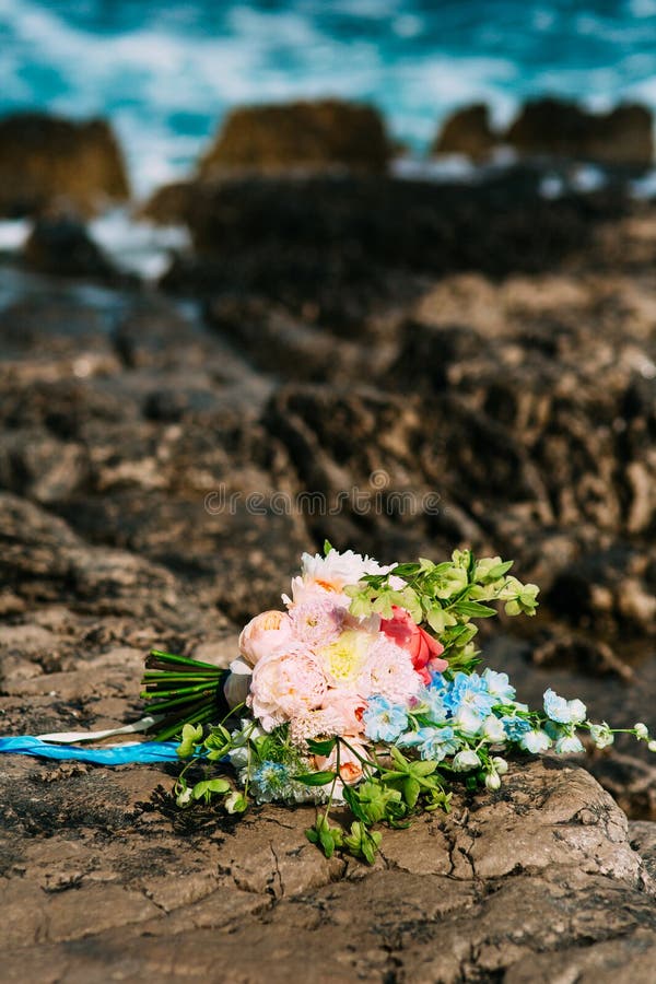 Wedding bouquet of peonies on the rocks by the sea. Wedding in M. Closeup, bride.