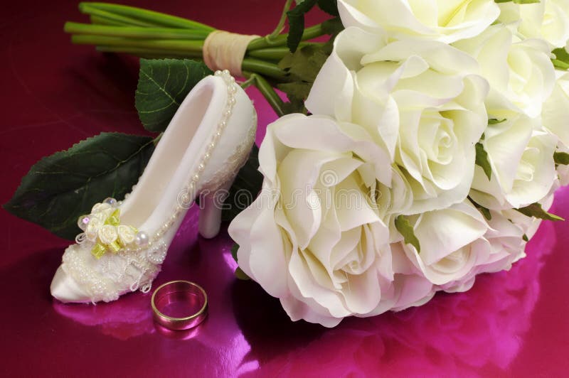 Wedding bridal bouquet of white roses with shoe and ring.