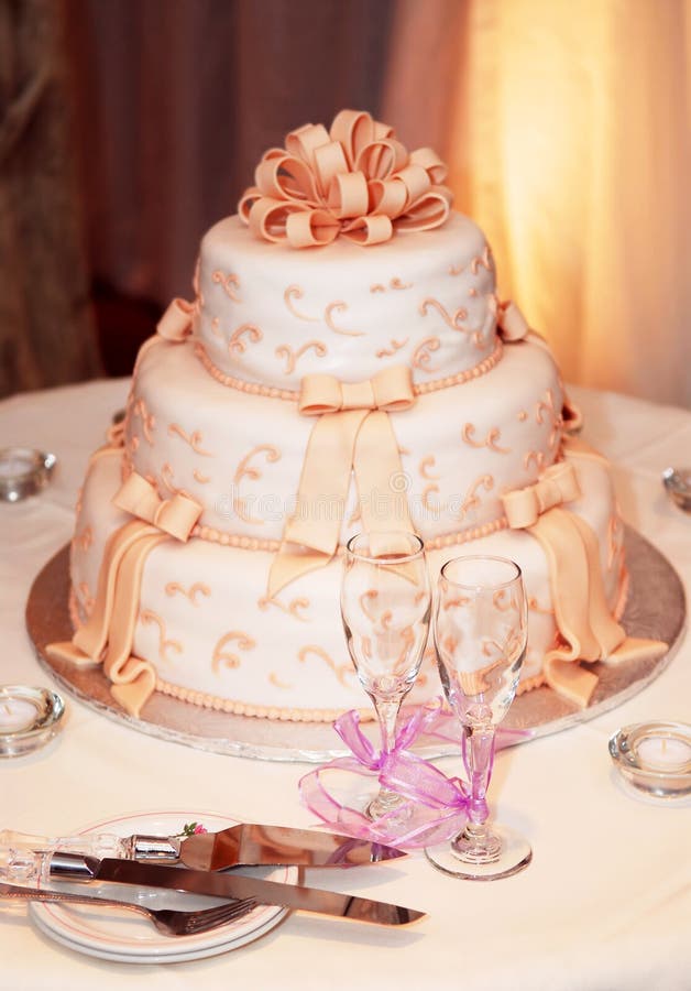 Three tiered wedding cake and champagne glasses on a table