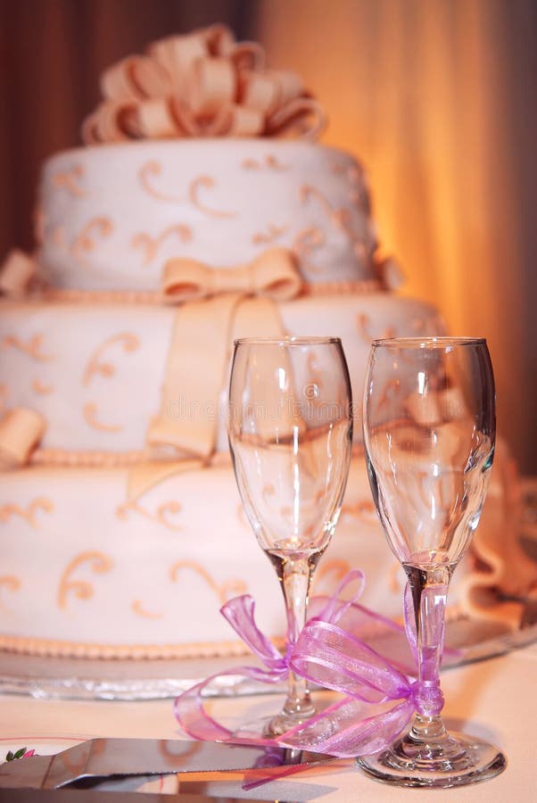 Three tiered wedding cake and champagne glasses on a table