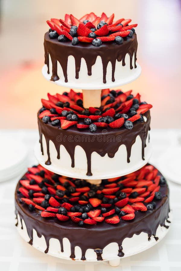 Wedding Cake with Strawberries and Blueberries in Chocolate Glaze Stock