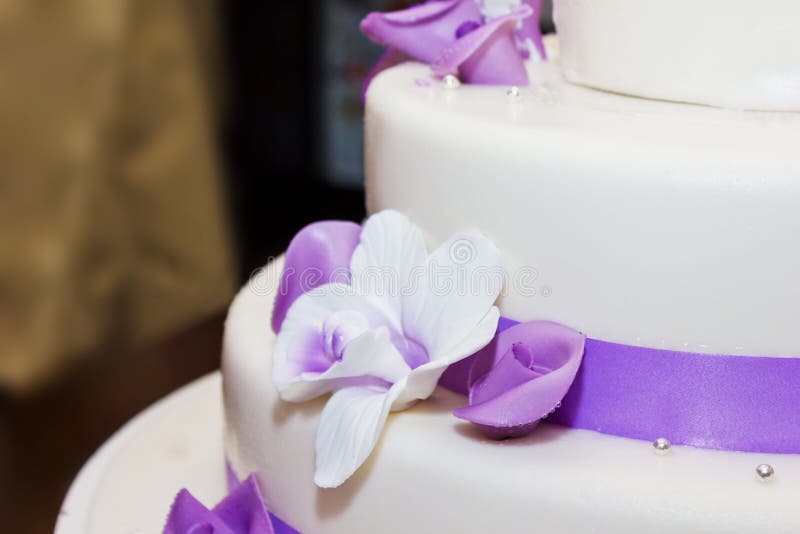 Tall wedding cake with purple ribbon and flower decorations