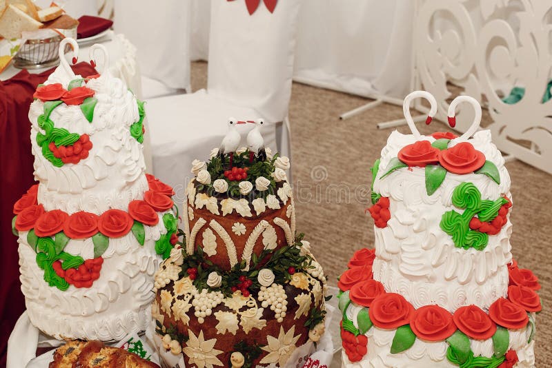 Wedding cakes with swans and storks on top, decorated with flower ornaments and red roses. birthday, baby shower. wedding