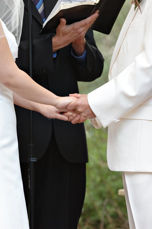 A close up of bride and groom holding hands during wedding ceremony