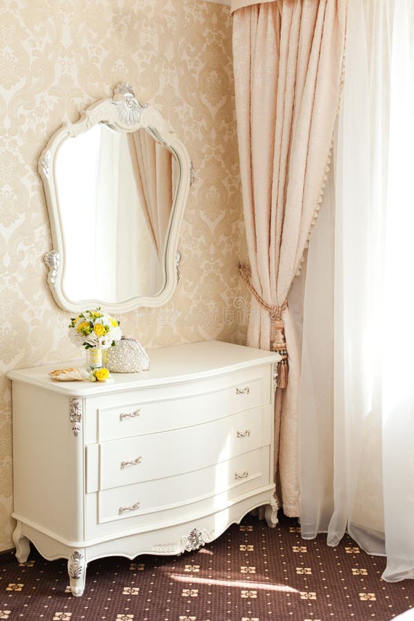 Elegant white commode dressing table with beautiful mirror and wedding bouquet from yellow flowers on it. Elegant white commode dressing table with beautiful mirror and wedding bouquet from yellow flowers on it