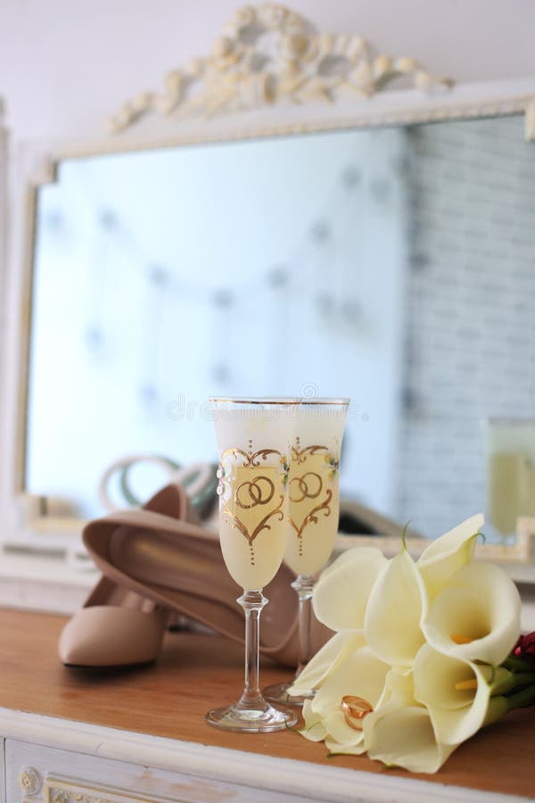 Wedding champagne glasses, wedding rings in white callas flowers, shoes and a mirror in the background stock photography Wedding champagne glasses, wedding rings in white callas flowers, shoes and a mirror in the background stock photography
