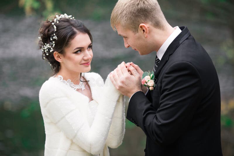 Wedding couple outdoors is hugging each other. Beautiful model girl in white dress. Man in suit. Beauty bride with groom. Female a stock photo Wedding couple outdoors is hugging each other. Beautiful model girl in white dress. Man in suit. Beauty bride with groom. Female a stock photo