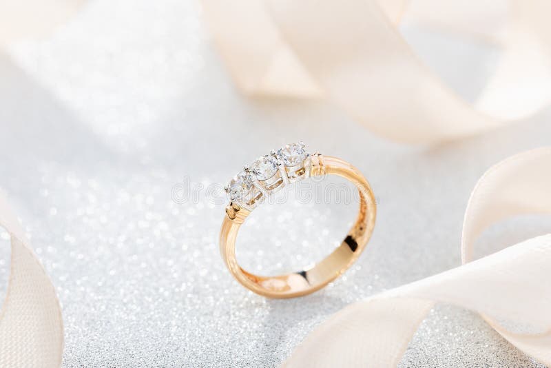 Wedding diamond ring on glossy background with beige ribbon