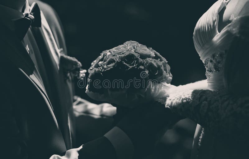 Wedding elegant couple bride and groom holding beautiful bouquet flowers closeup, black and white photo closeup