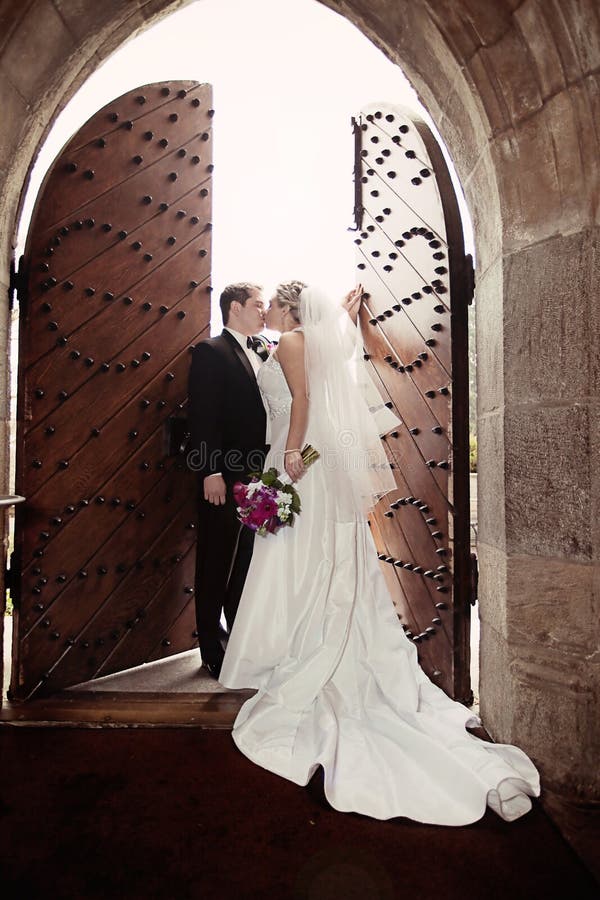 Ženich líbat jeho nevěsta v přední části otevřeného starý zámek dveří.