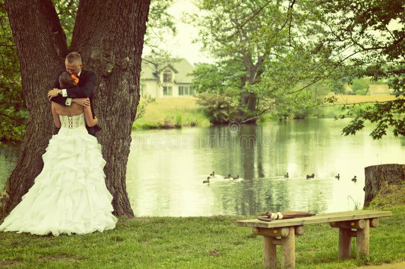 Bride and groom hugging at the wedding held in a park. Bride and groom hugging at the wedding held in a park.