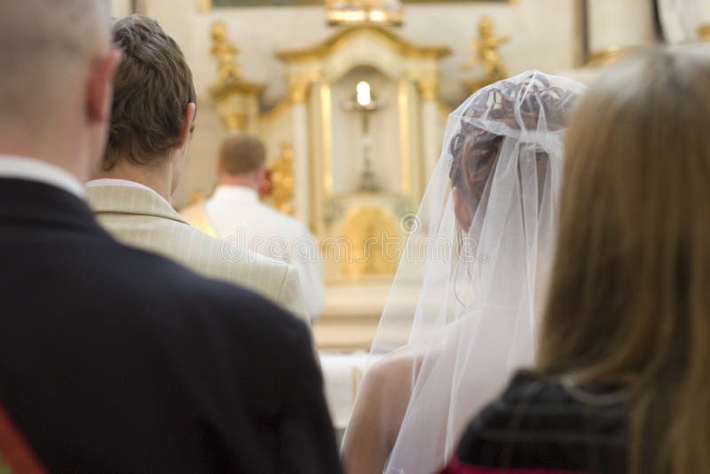 A view of a wedding couple and their witnesses as they stand at the altar during a marriage ceremony in a Catholic Church. A view of a wedding couple and their witnesses as they stand at the altar during a marriage ceremony in a Catholic Church.