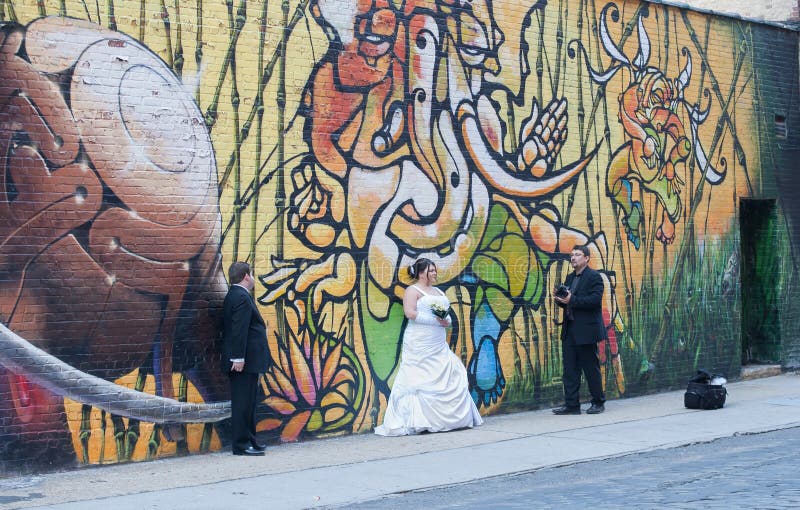 Wedding Photographer & Clients in front of Graffiti Wall. Wedding Photographer takes his Clients to Dumbo Brooklyn for a fabulous Graffiti Wall Background royalty free stock photo Wedding Photographer & Clients in front of Graffiti Wall. Wedding Photographer takes his Clients to Dumbo Brooklyn for a fabulous Graffiti Wall Background royalty free stock photo