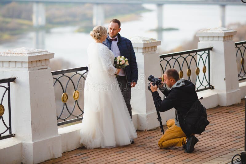 Wedding photographer taking pictures of the bride and groom on park alley