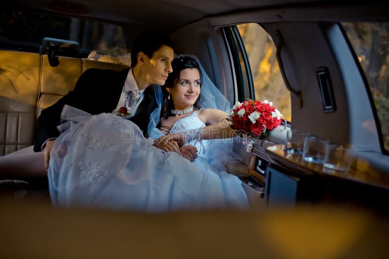 Wedding portrait. Happy young stylishly dressed couple is sitting in the car and looking through window. The bride with royalty free stock images Wedding portrait. Happy young stylishly dressed couple is sitting in the car and looking through window. The bride with royalty free stock images