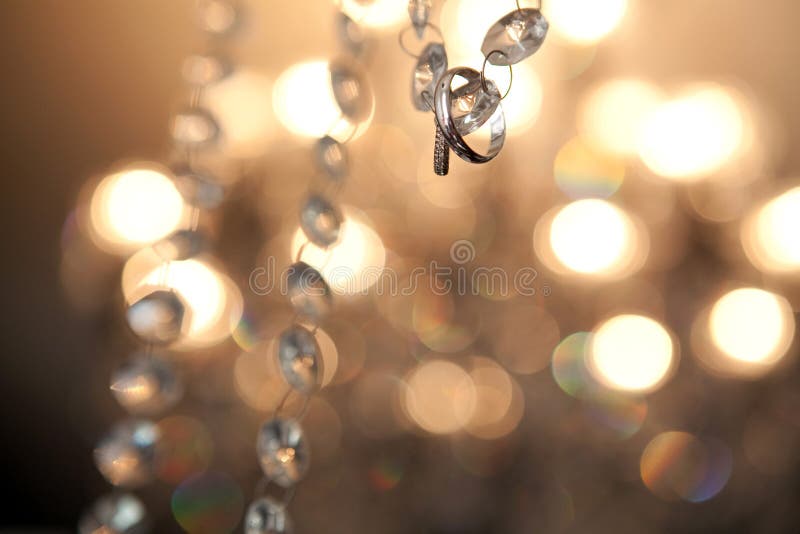 Wedding rings hanging on crystal stripe with bokeh as background