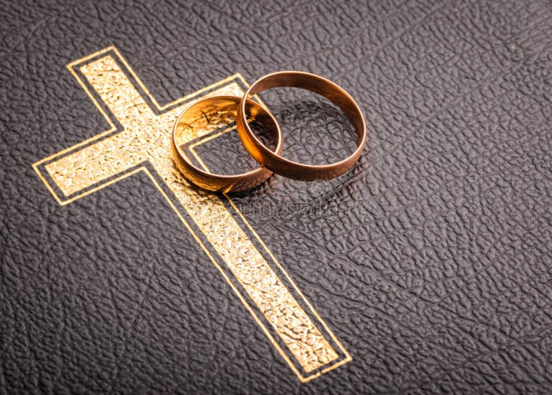 Wedding rings on the Bible with the cross of Christianity