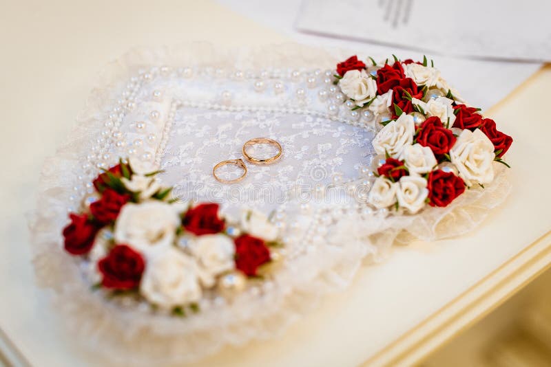 Wedding rings on a heart-shaped pillow with flowers stock images Wedding rings on a heart-shaped pillow with flowers stock images