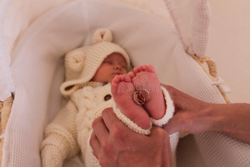 Gold wedding rings lying on small feet and heels of a 2 month old baby girl sleeping in her crib. Gold wedding rings lying on small feet and heels of a 2 month old baby girl sleeping in her crib