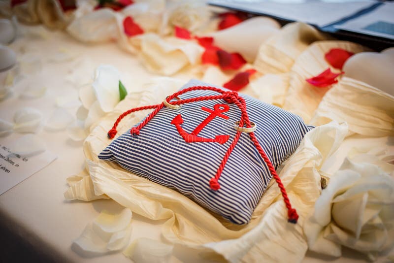 Wedding rings together with red rope on striped pillow with anchor on it. Marriage ceremony stock photo Wedding rings together with red rope on striped pillow with anchor on it. Marriage ceremony stock photo