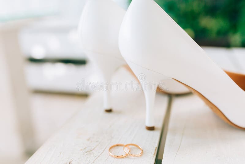 Wedding rings and wedding shoes bride. Gold, background.