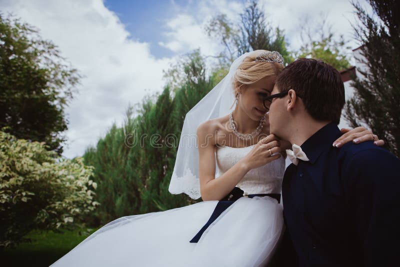 Wedding Shot of Bride and Groom Sit on Bench in Park Stock Photo