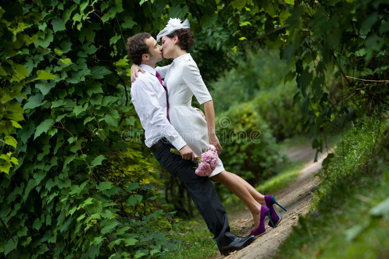 Wedding theme. The groom kisses the bride in a botanical garden royalty free stock photography