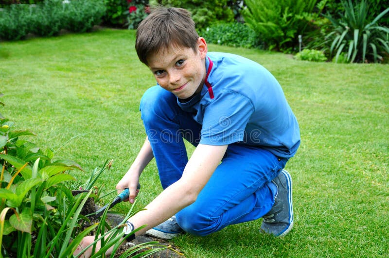 Adolescente ragazzo diserbo letti in giardino.