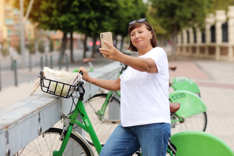 Weekend Ride On Bicycle Mature Woman Renting Bike Using Smartphone For Selfie Stock Image 