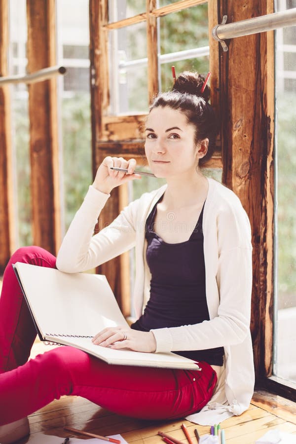 Wei?er kaukasischer junger brunette weiblicher K?nstler der Studentin, der auf Boden in der Collegeuniversit?t sitzt lizenzfreie stockfotografie Wei?er kaukasischer junger brunette weiblicher K?nstler der Studentin, der auf Boden in der Collegeuniversit?t sitzt lizenzfreie stockfotografie
