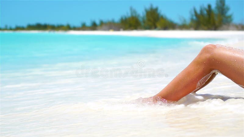 Weiblich nehmen Sie gebräunte Beine auf einem weißen tropischen Strand ab Langsames Video