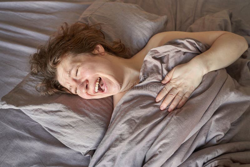 Weibliche erwachsene kaukasische Frauen lachen mit grauer Decke im Bett und warmes natürliches Licht lizenzfreies stockfoto
