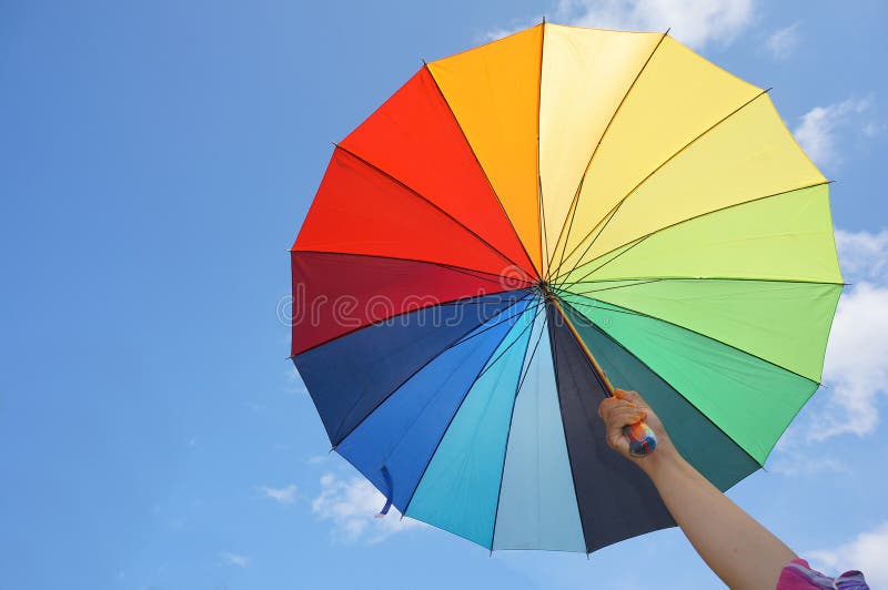 Weibliche Hand, die mehrfarbigen Regenschirm hält stockbilder Weibliche Hand, die mehrfarbigen Regenschirm hält stockbilder