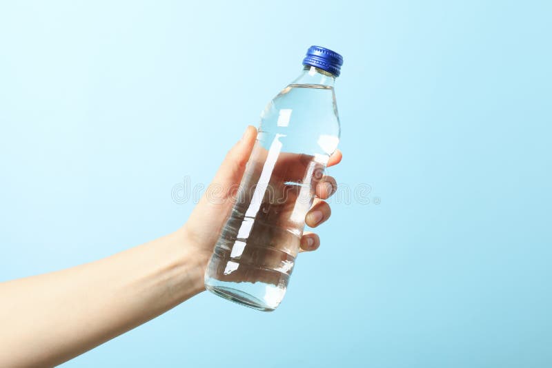 Weibliche Hand hält Flasche mit Wasser auf Hintergrundabschluß oben lizenzfreie stockfotos