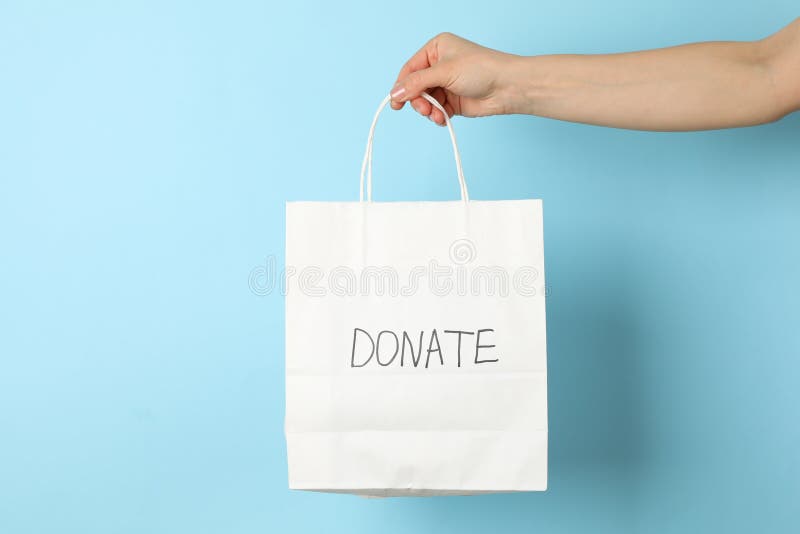Weibliche Hand hält Papiertüte mit Billigung, Blau zu spenden stockbild