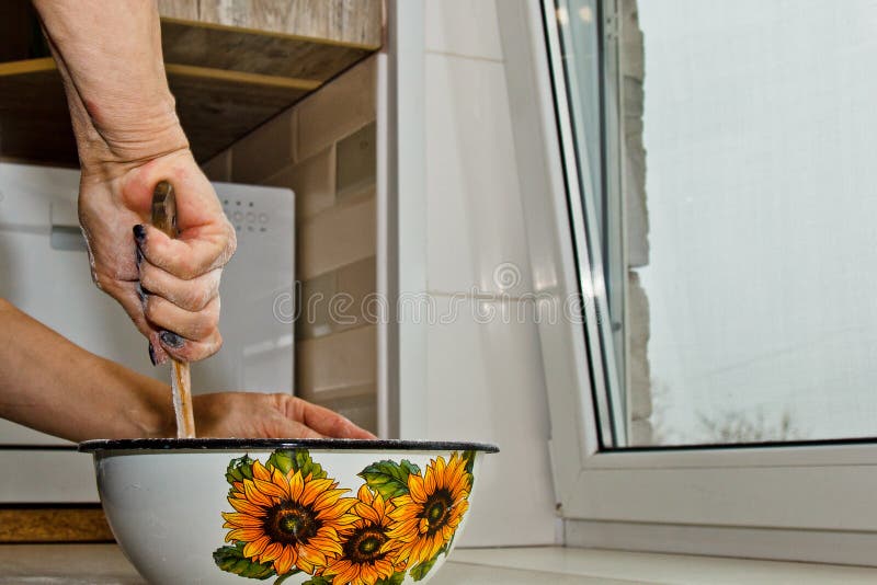 Weibliche Hand knetet Teig von der Milch von Butter und von Mehl in einer Metallsch?ssel mit einem h?lzernen Schneebesen in der K stockfoto Weibliche Hand knetet Teig von der Milch von Butter und von Mehl in einer Metallsch?ssel mit einem h?lzernen Schneebesen in der K stockfoto