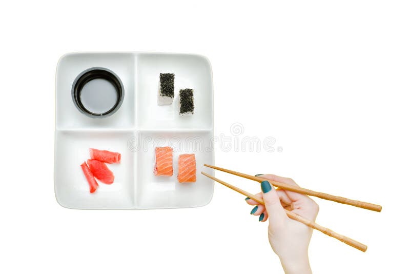 Weibliche Hand mit Essstäbchen und Platte mit Sushi auf einem gelben BAC stockbild Weibliche Hand mit Essstäbchen und Platte mit Sushi auf einem gelben BAC stockbild