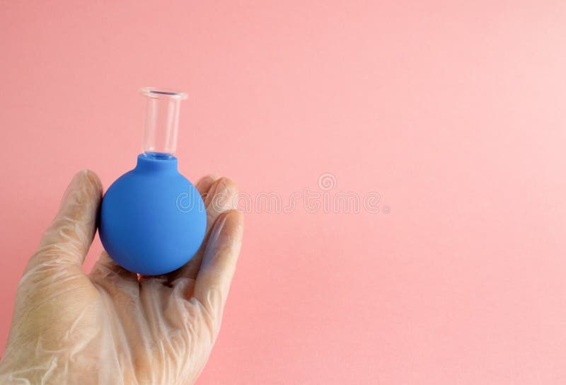Weibliche Hand mit französischer Maniküre im Medizinhandschuh hält blaues kosmetisches medizinisches Glas für Vakuumgesichtsmassa lizenzfreie stockfotografie Weibliche Hand mit französischer Maniküre im Medizinhandschuh hält blaues kosmetisches medizinisches Glas für Vakuumgesichtsmassa lizenzfreie stockfotografie