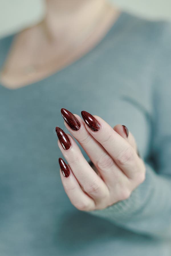 Weibliche Hand mit langen Nägeln und dunkelrote Maniküre stockbild