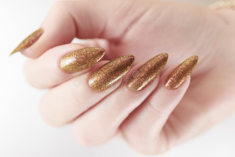 Weibliche Hand mit langen Nägeln und eine Flasche hellgelb goldgelber Nagellack stockbilder