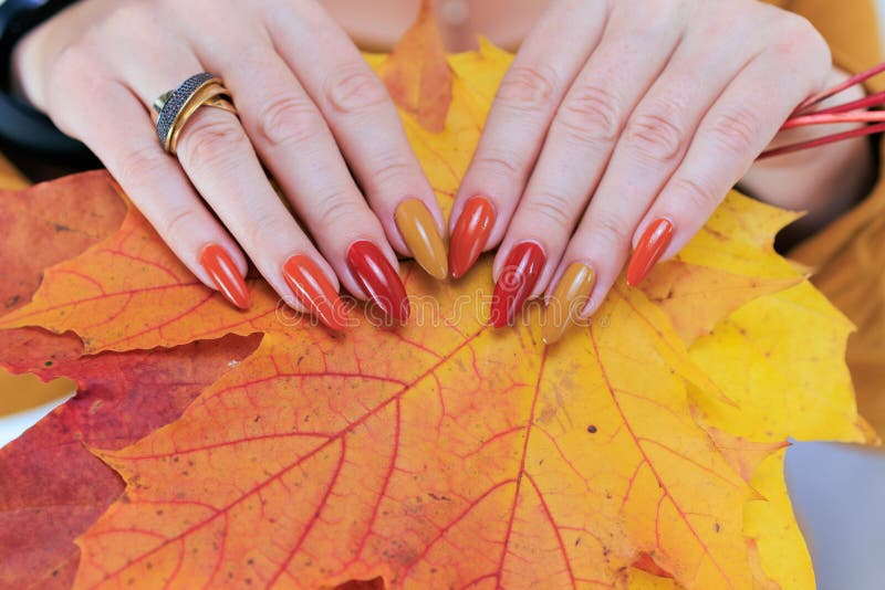 Weibliche Hand mit langen Nägeln und gelb-orangefarbener Nagellack lizenzfreie stockfotografie
