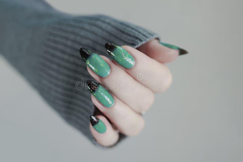 Weibliche Hand mit langen Nägeln und grünschwarz-thermo-französischer Maniküre stockfotos