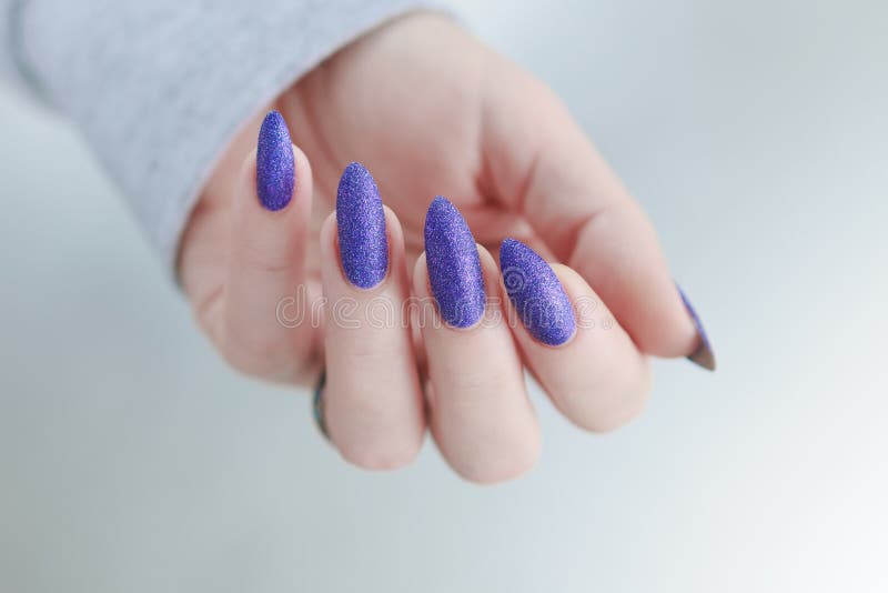 Weibliche Hand mit langen Nägeln und lila Pflaumenmaniküre stockfotos