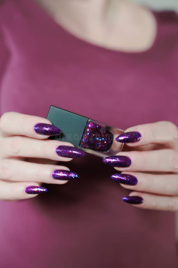 Weibliche Hand mit langen Nägeln und lila Pflaumenmaniküre stockfoto