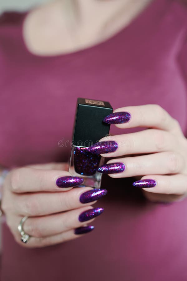 Weibliche Hand mit langen Nägeln und lila Pflaumenmaniküre stockfotografie